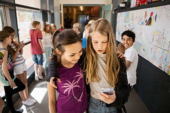 Tween girls looking at cell phone at school