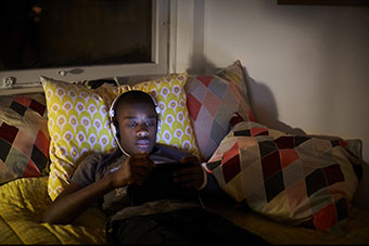 Teen in bed on electronics