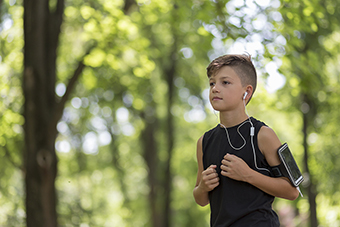 Tween boy running outside with iPod
