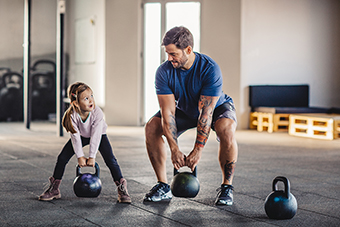 Dad and daughter exercising together with kettlebells