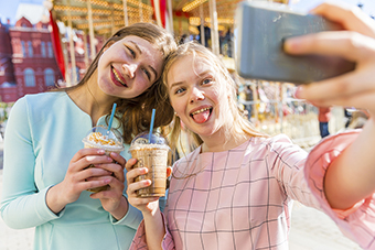 Teen girls drinking frozen coffee and taking a selfie