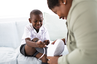 Mom helping son tie his new shoes