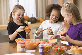 Three young girls frosting cupcakes