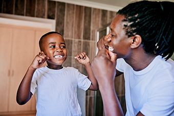Dad and young son flossing teeth together