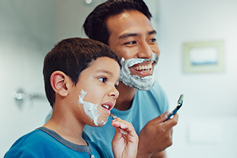 Dad teaching young son how to shave