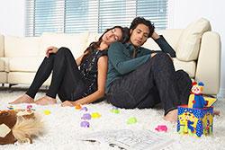 tired parents on the floor with kids' toys