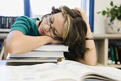 Teen asleep on stack of books